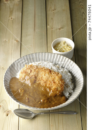 大きい豚カツが真ん中に一枚乗っている熱々カツカレーとトッピングのチーズとスプーン 74476041