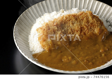 大きい豚カツが真ん中に一枚乗っているカツカレーを黒背景で撮影 74476156
