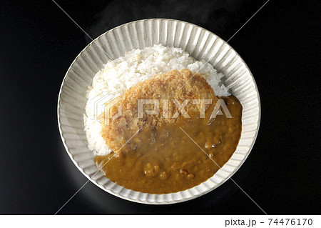 大きい豚カツが真ん中に一枚乗っている熱々カツカレーを黒背景で撮影（俯瞰） 74476170