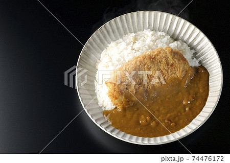 大きい豚カツが真ん中に一枚乗っている熱々カツカレーを黒背景で撮影(俯瞰) 大きい豚カツが真ん中に一枚乗っている熱々カツカレーを黒背景で撮影(俯瞰) 74476172