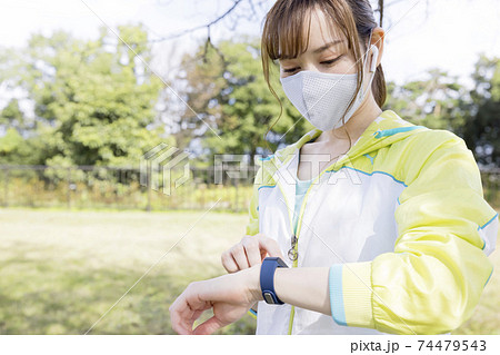 トレーニング前にスマートウォッチを操作するマスク姿の若い女性 トレーニング前にスマートウォッチを操作するマスク姿の若い女性 74479543