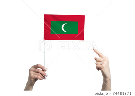 A beautiful female hand holds a Maldives flag to which she shows the finger of her other hand, isolated on white background A beautiful female hand holds a Maldives flag to which she shows the finger of her other hand, isolated on white background 74481371