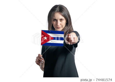 Happy young white woman holding flag of Cuba and points forward in front of him isolated on a white background Happy young white woman holding flag of Cuba and points forward in front of him isolated on a white background 74481574