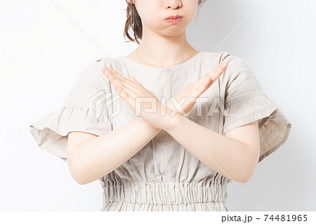 白背景の前に立って、NGのジェスチャーをする若い女性 74481965