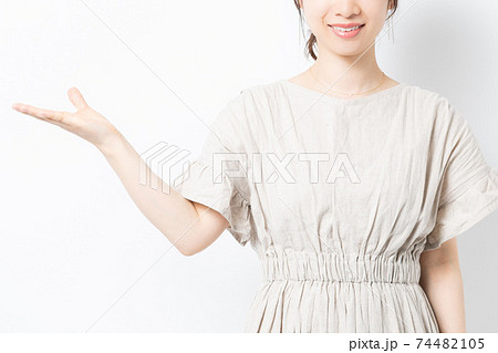 白背景の前で案内のジェスチャーをする若い女性 74482105