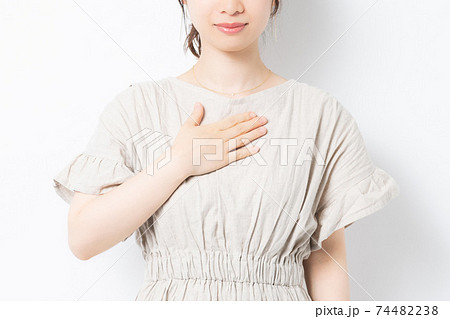 白背景の前に立って胸に手を当てる若い女性 74482238