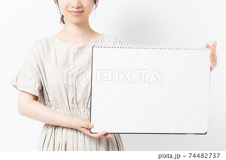 白背景の前でスケッチブックを持つ若い女性の写真素材 [74482737] - PIXTA