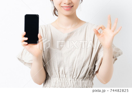 白背景の前に立ってスマホを持っている若い女性 白背景の前に立ってスマホを持っている若い女性 74482825