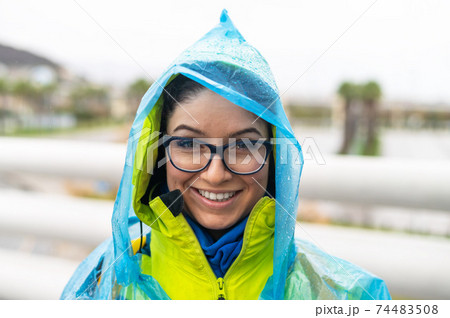 Portrait of a smiling woman with glasses wearing a raincoat outdoors. Portrait of a smiling woman with glasses wearing a raincoat outdoors. 74483508
