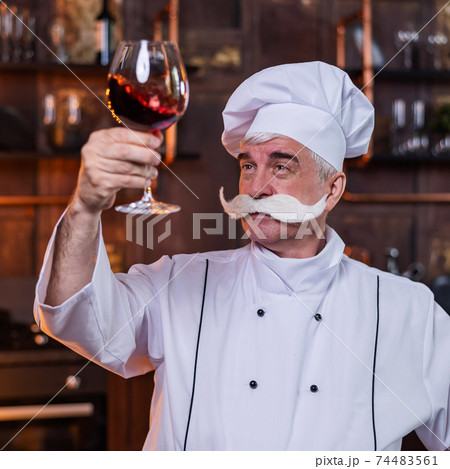 An elderly male chef degustation red wine in the kitchen An elderly male chef degustation red wine in the kitchen 74483561