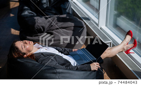 Business lady sleeps sitting in a modern office comfortable bob chair bag. A woman in a suit fell asleep at work on a laptop. Caring for the convenience and comfort of employees. Business lady sleeps sitting in a modern office comfortable bob chair bag. A woman in a suit fell asleep at work on a laptop. Caring for the convenience and comfort of employees. 74484043
