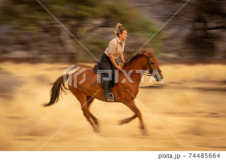 Slow pan of blonde riding through savannah 74485664