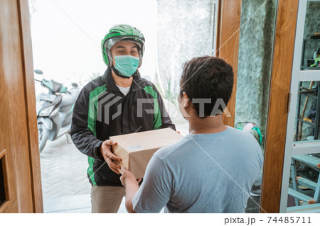 delivery courier wear face masks while delivering package 74485711