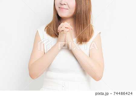 白背景の前でお願いのジェスチャーをする若い女性 白背景の前でお願いのジェスチャーをする若い女性 74486424