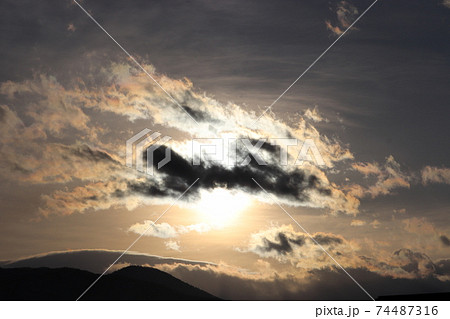 太陽光が周りの雲に反射して神々しさを表現している夕日の写真素材