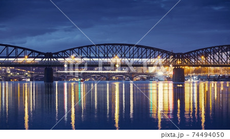 Passenger train passing over railway bridge against city Passenger train passing over railway bridge against city 74494050