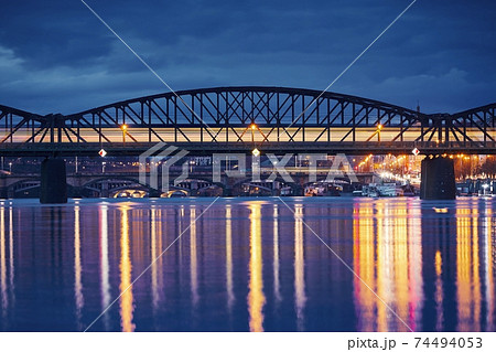 Passenger train passing over railway bridge against city 74494053