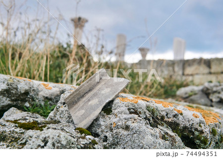 shard of ancient ceramics on a stone against a background of blurry ancient ruins 74494351