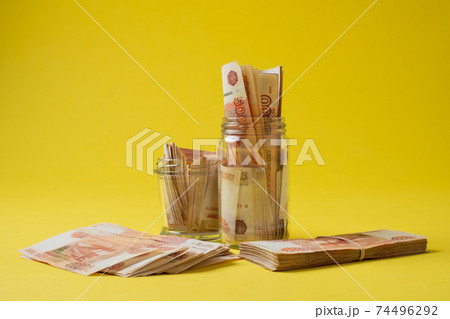 Many russian bank notes in a glass jar isolated on yellow background 74496292