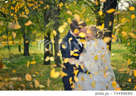 a kiss of a newly-married couple in an autumn park 74499680