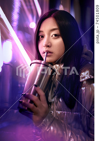 Young adult trendy woman in glowing neon light drinking beverage Young adult trendy woman in glowing neon light drinking beverage 74501809