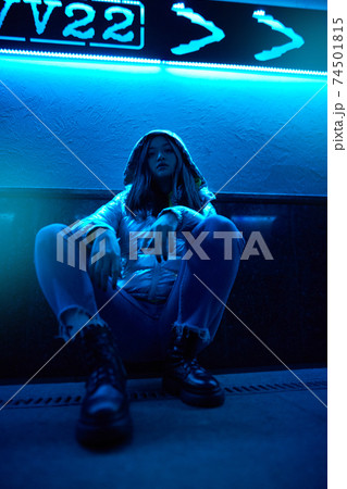 Young adult hipster woman sitting under glowing neon light 74501815