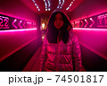 Neon Style. Asian girl in glossy jacket standing in the corridor with fluorescent pink lights looking camera confident 74501817