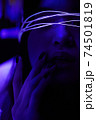 Young adult millennial woman in bright neon light, touching her lips with fingers 74501819