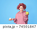 Girl in hoodie preferring fresh green apple to sweet cupcake 74501847