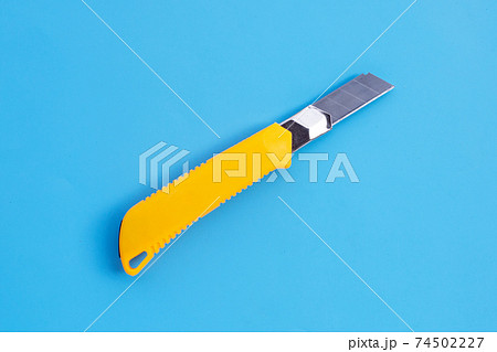 Stationery knife on blue background. Stationery knife on blue background. 74502227
