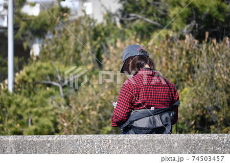 公園でくつろぐ若い女性の後ろ姿の風景 74503457