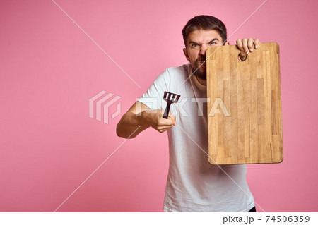 guy holding kitchen board and spatula in hand on pink background cropped view 74506359