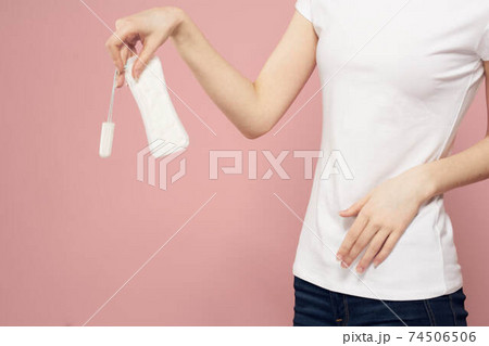 Girl with a pad and tampons in hand pink background menstruation critical days hygiene 74506506
