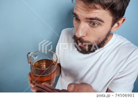 Cheerful man in a white T-shirt with a beer mug drunk blue background Cheerful man in a white T-shirt with a beer mug drunk blue background 74506901