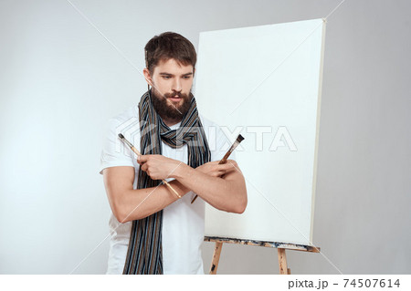 Male artist brush in hands of easel art hobby light background scarf around his neck 74507614