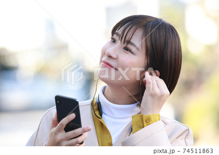 スマートフォンで音楽を聴く女性 74511863