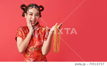 Attractive chinese asian female in tradition dress is holding gold necklace with joy and cheerful. 74513737