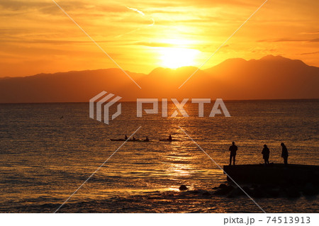 片瀬江ノ島海岸から見る伊豆半島に沈むオレンジ色の夕日と堤防のシルエット 74513913