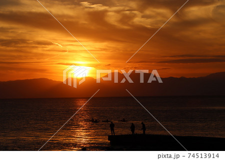 片瀬江ノ島海岸から見る伊豆半島に沈むオレンジ色の夕日と堤防のシルエット 74513914