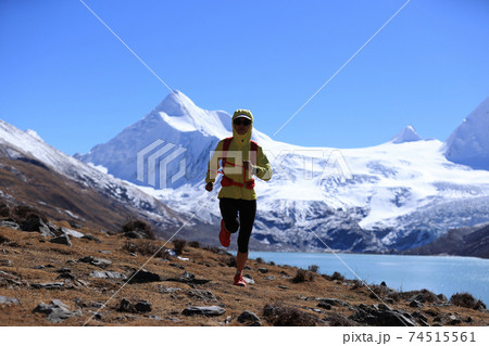Woman trail runner cross country running  in winter mountains 74515561