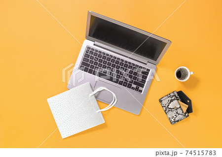 Laptop with shopping bags on trendy yellow orange background Laptop with shopping bags on trendy yellow orange background 74515783