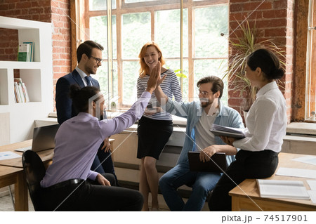 Overjoyed multiracial male colleagues give high five Overjoyed multiracial male colleagues give high five 74517901