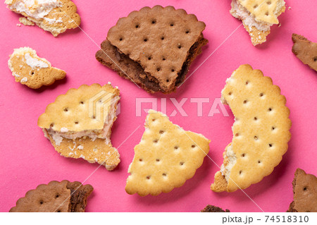 Pieces of chocolate chip cookies and biscuits with filling on a pink background close-up 74518310