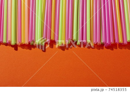 Colored tubules for juice and cocktails on orange background. Space for text. 74518355