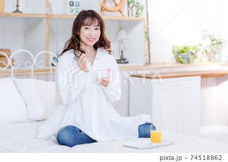 ベッドでヨーグルトを食べる若い女性 ベッドでヨーグルトを食べる若い女性 74518862