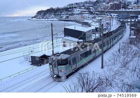 冬の東小樽海水浴場脇を行く函館本線の普通列車の写真素材