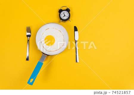 alarm clock and scrambled eggs on a yellow background with space to copy. for good morning 74521857