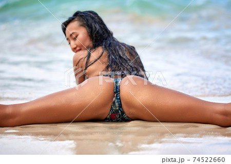 Sexy girl sitting in a splits at the sand inthe tropical beach 74522660