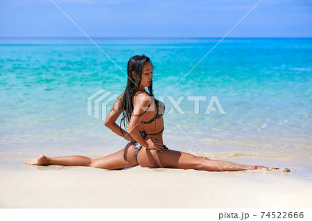 Sexy girl sitting in a splits at the sand inthe tropical beach Sexy girl sitting in a splits at the sand inthe tropical beach 74522666