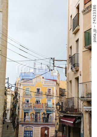 スペインバルセロナ郊外の町タラゴナの街並み アパートの住人の絵が描かれた建物細道の両脇に並ぶアパートの写真素材